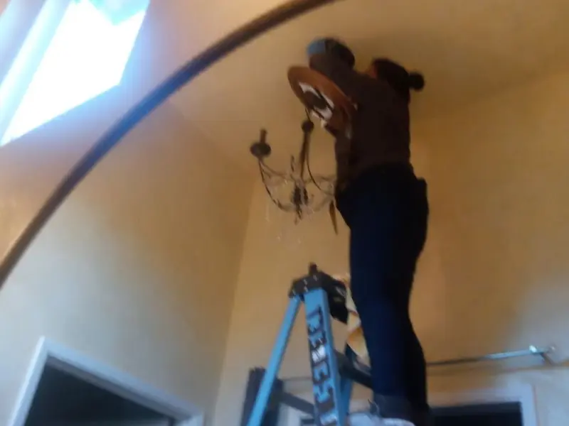 Electrician installing a chandelier in a Lemay residence